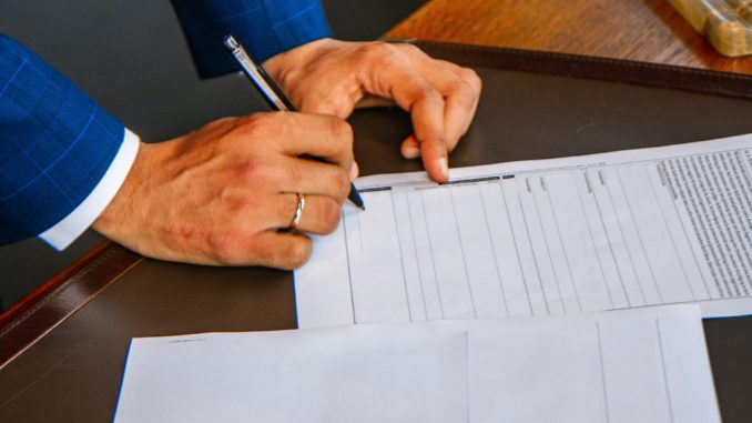 person writing on white form paper